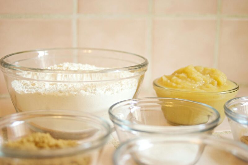 Bowls of flour, brown sugar, and applesauce on a kitchen counter