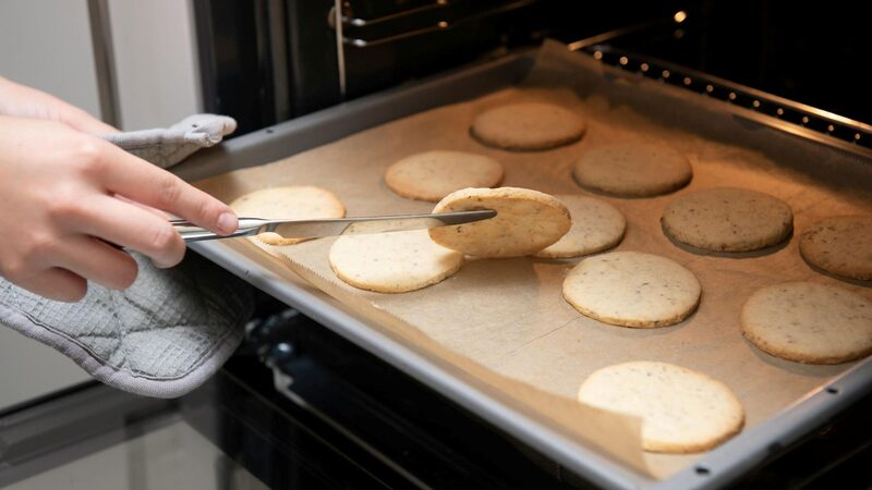 Cookies on a parchment-lined baking sheet being slid into the oven