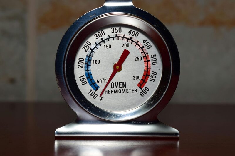 A stainless steel oven thermometer reading temperature