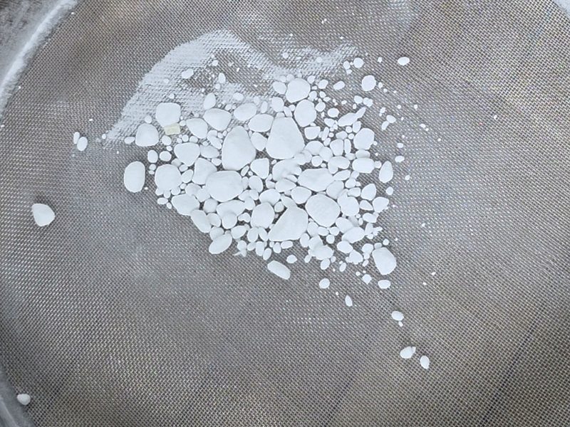 Hard baking soda clumps caught on top of a fine-mesh sieve