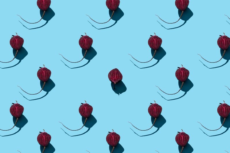 Repeating pattern of red beets on a bright blue background