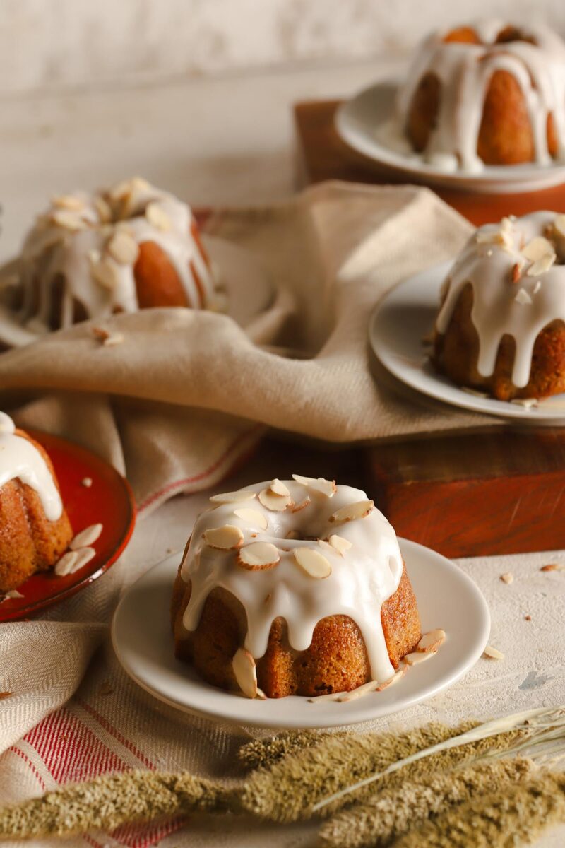 A glazed gluten-free mini bundt cake with almonds on a plate