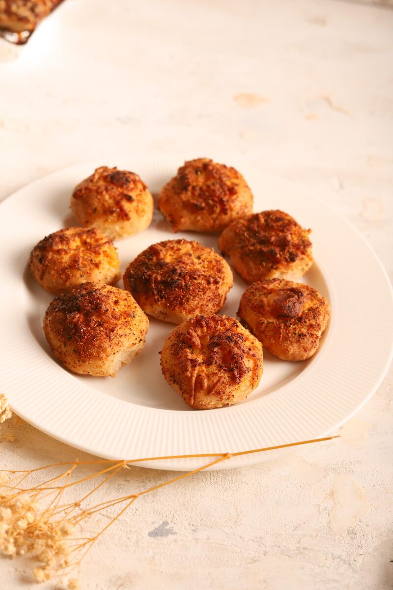 A plate of baked cheesy rolls scattered with garlic and herbs