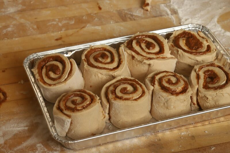 Shaped cinnamon rolls arranged in a greased baking tray