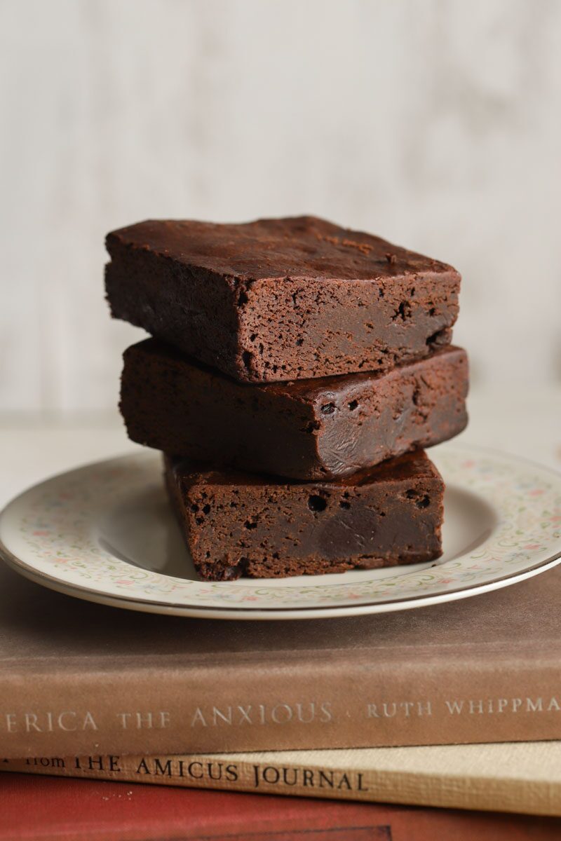 Vegan gluten-free chocolate brownies stacked on a white plate