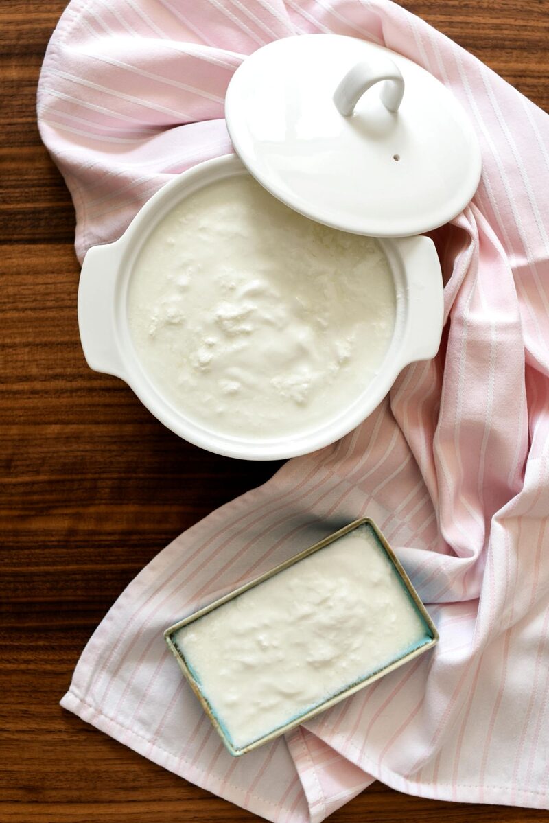 A ceramic pot and a metal cake pan full of freshly made yogurt