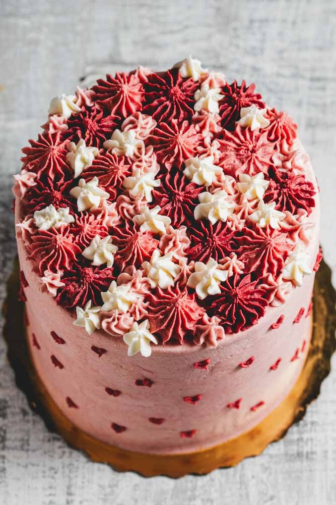 Pink buttercream layer cake with rosettes and tiny red heart accents