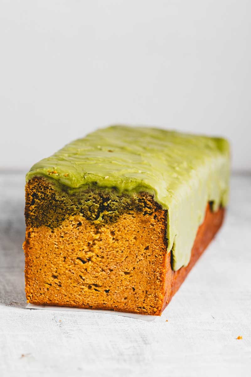 Loaf cake with thick matcha green glaze on a white surface