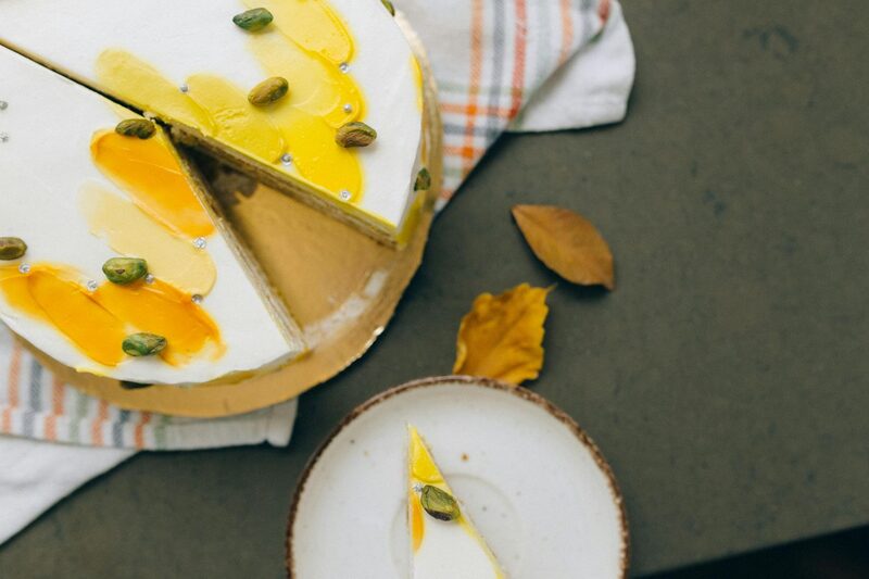 Cake with bright yellow brushstrokes of glaze topped with pistachios