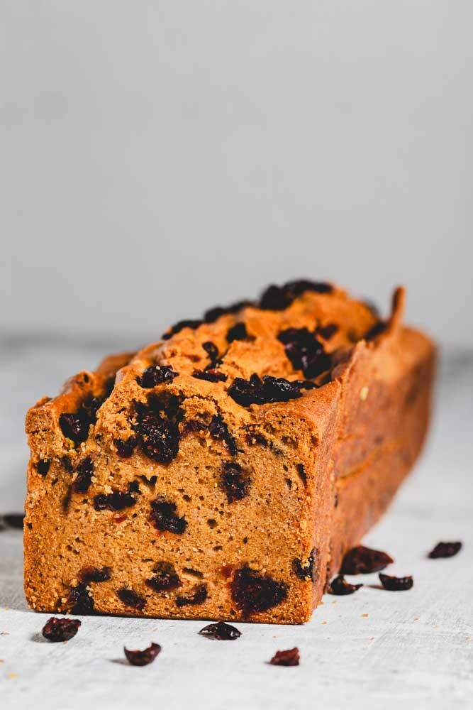 A pumpkin chia loaf with a slice cut off to show cranberries inside