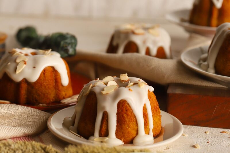 Glazed mini bundt cakes topped with sliced almonds on small plates