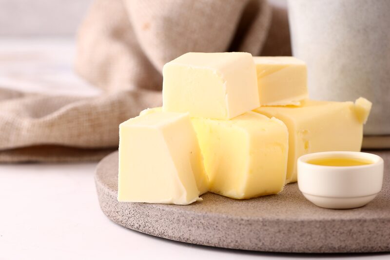 Cubes of butter stacked on a stone board beside a small dish of melted butter
