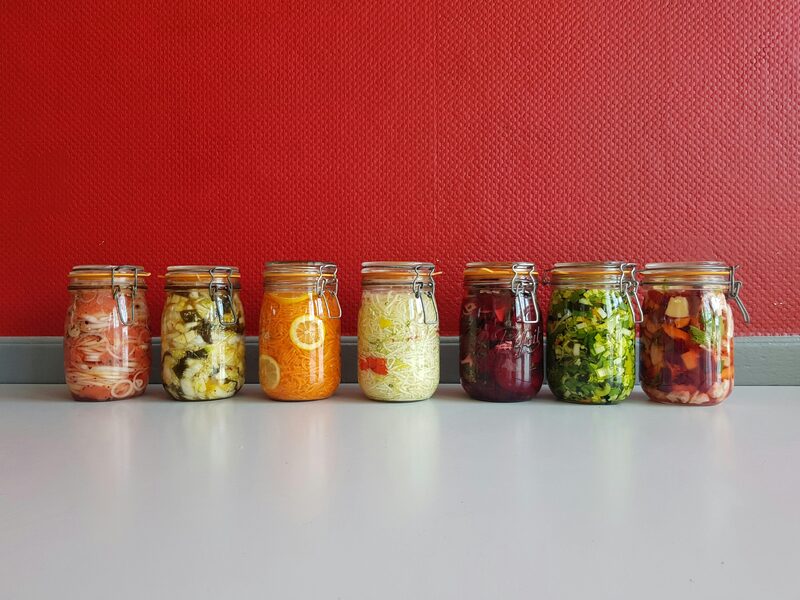 Row of glass jars filled with various fermented vegetables