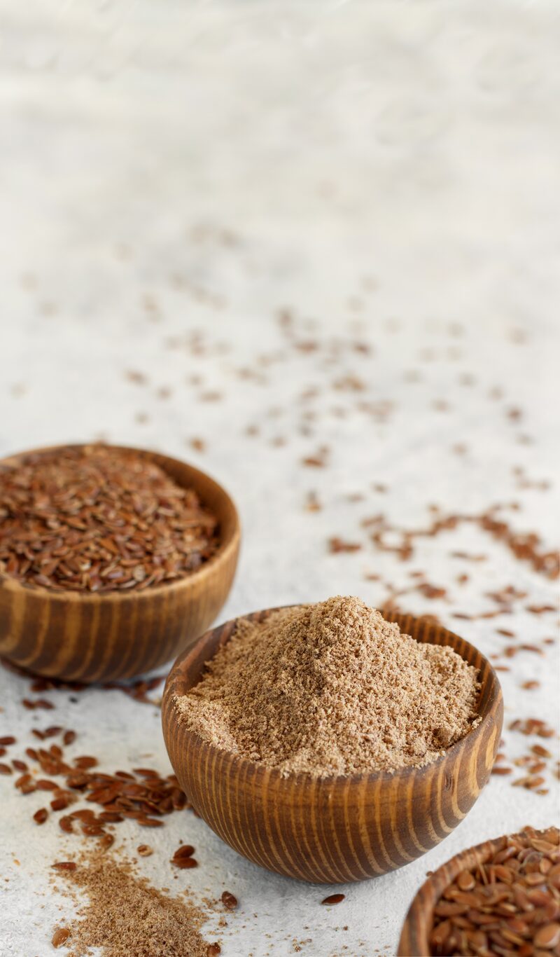 Whole flax seeds and ground flax meal in two small wooden bowls