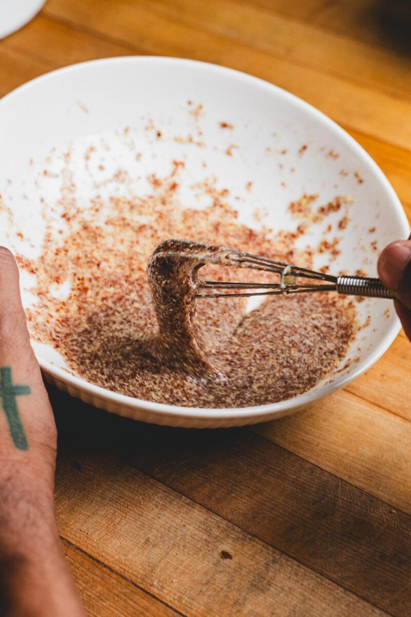 Whisking a flax egg into a thick brown gel in a white bowl