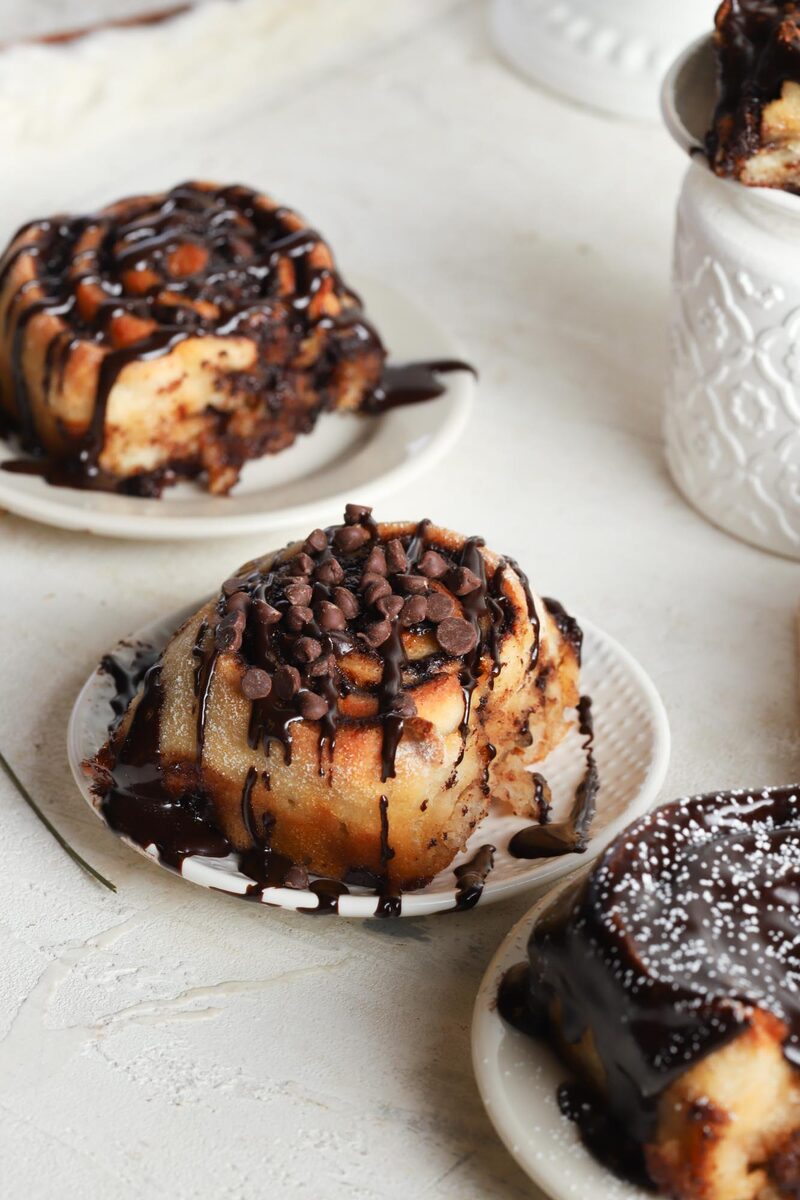 Gluten-free cinnamon rolls drizzled with chocolate and topped with mini chocolate chips
