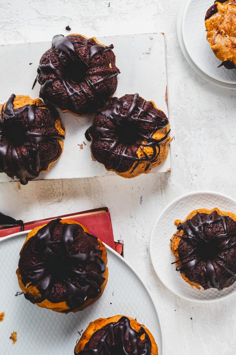 Mini chocolate-glazed gluten-free bundt cakes arranged on a board, shot from above
