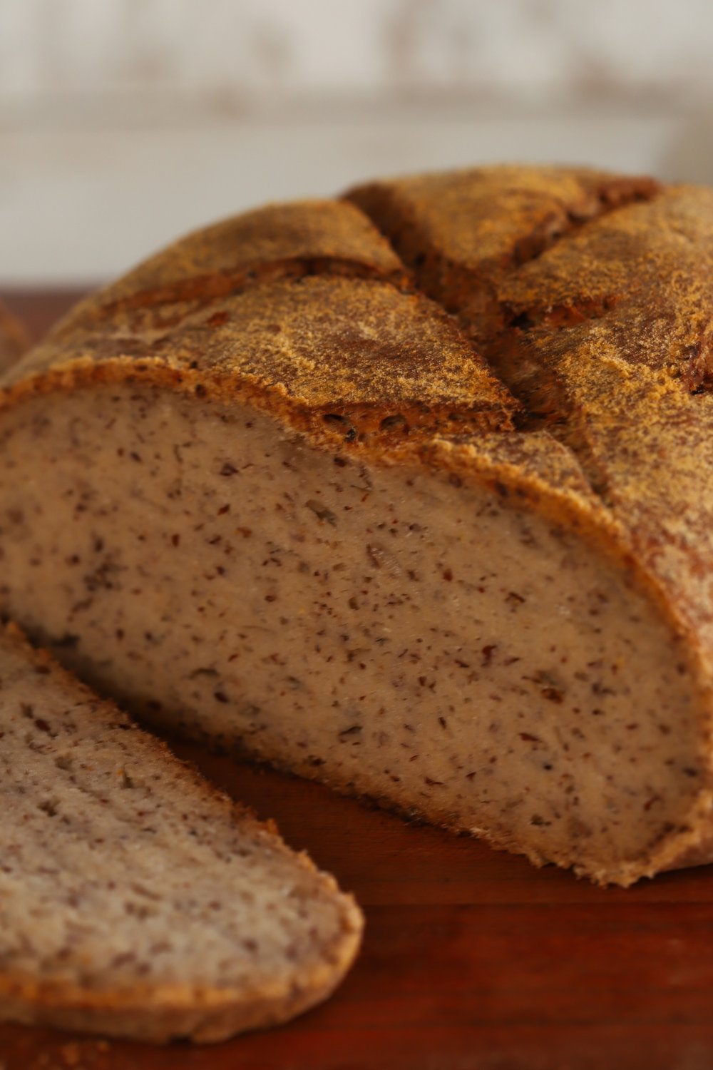 A sliced loaf of gluten-free flax and chia seed sourdough bread showing an open crumb