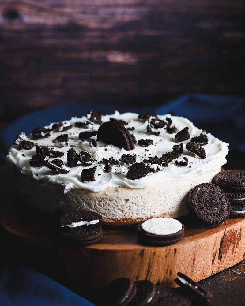 Cookies-and-cream cheesecake with a clean side, released intact onto a wooden board