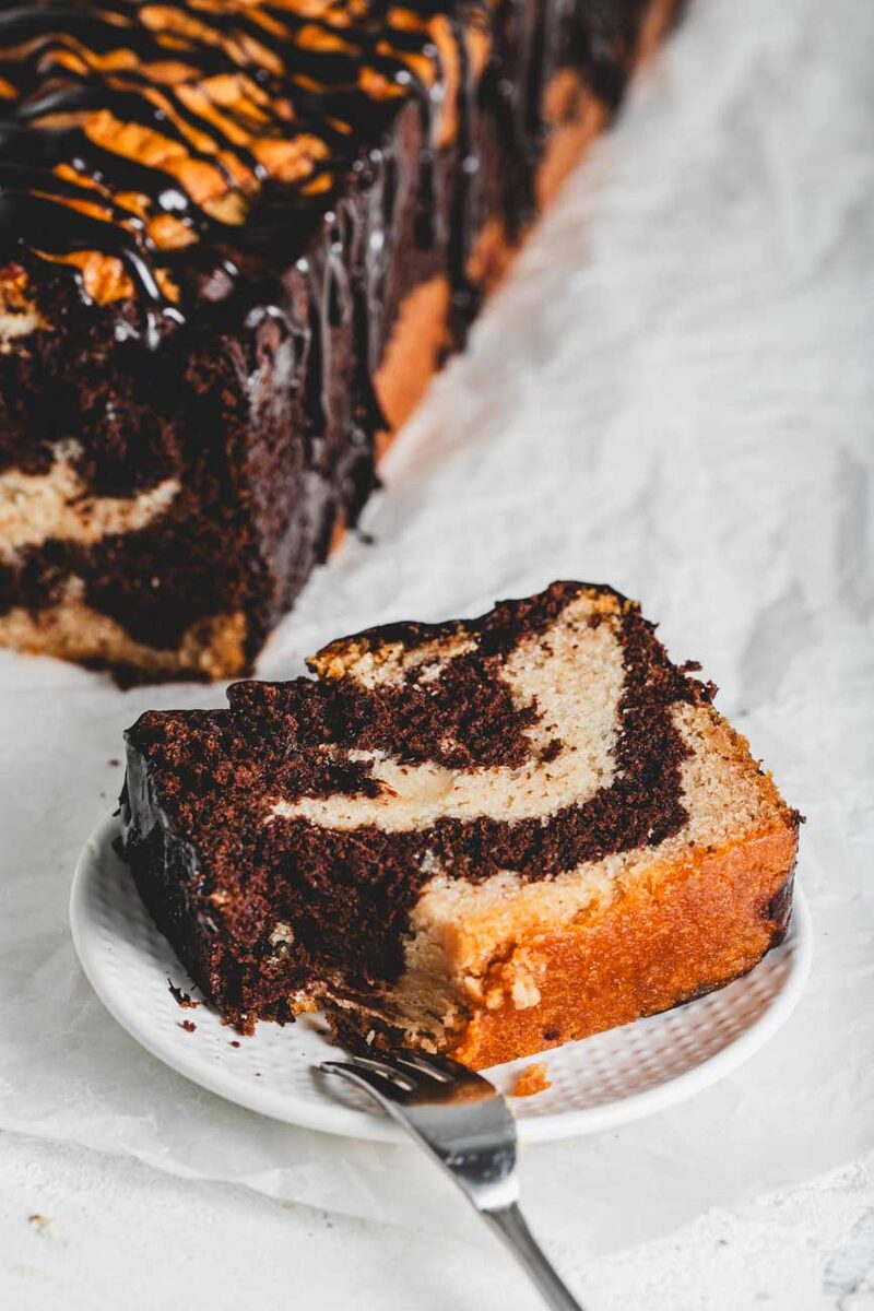 Slice of marble loaf cake with a chocolate drizzle showing a clean, intact edge