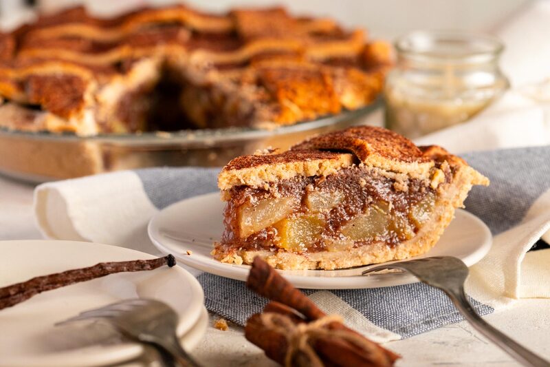 Slice of lattice-topped apple pie released cleanly onto a plate with forks alongside