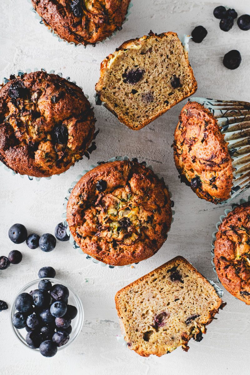 Domed blueberry muffins beside slices cut open to show an open, evenly risen crumb