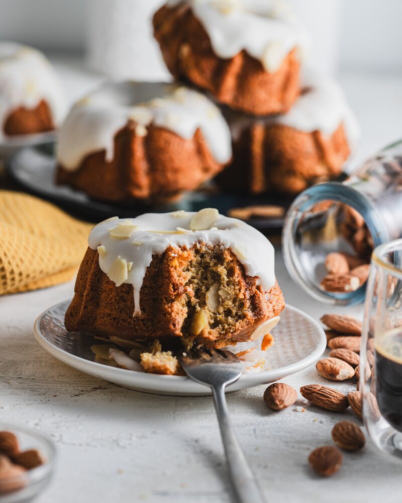 Glazed mini bundt cakes, one bitten open to show a tall, open crumb