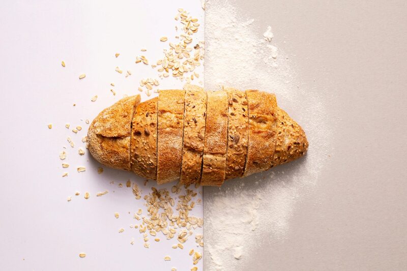 Sliced oat bread on a counter dusted with flour and rolled oats