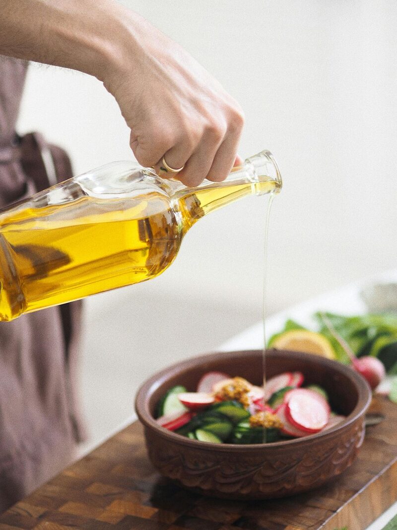 Pouring olive oil over a fresh salad of radishes and greens