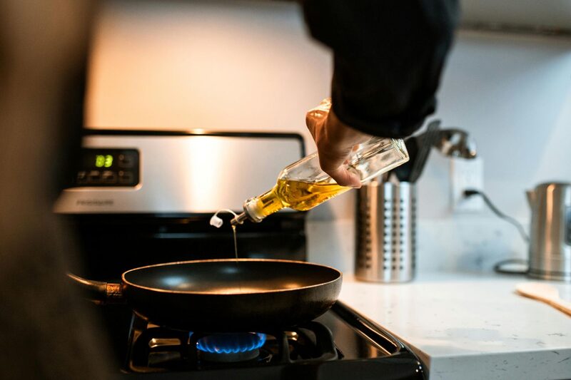 Pouring oil into a hot pan over a gas flame