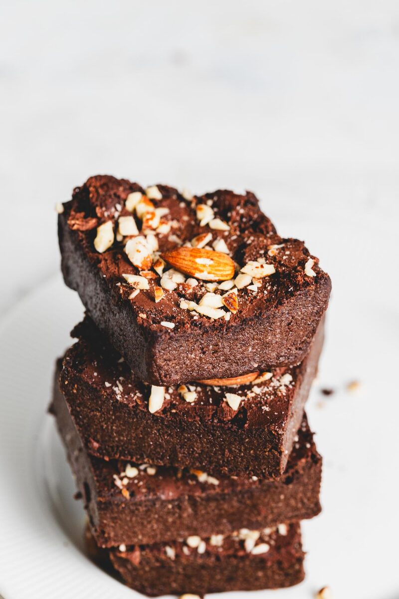 A stack of fudgy sugar-free protein brownies topped with chopped almonds