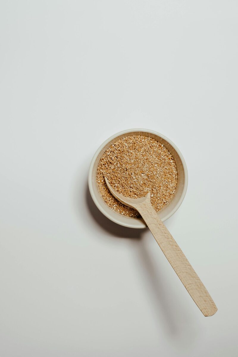 A bowl of psyllium husk with a wooden spoon in it on a white background