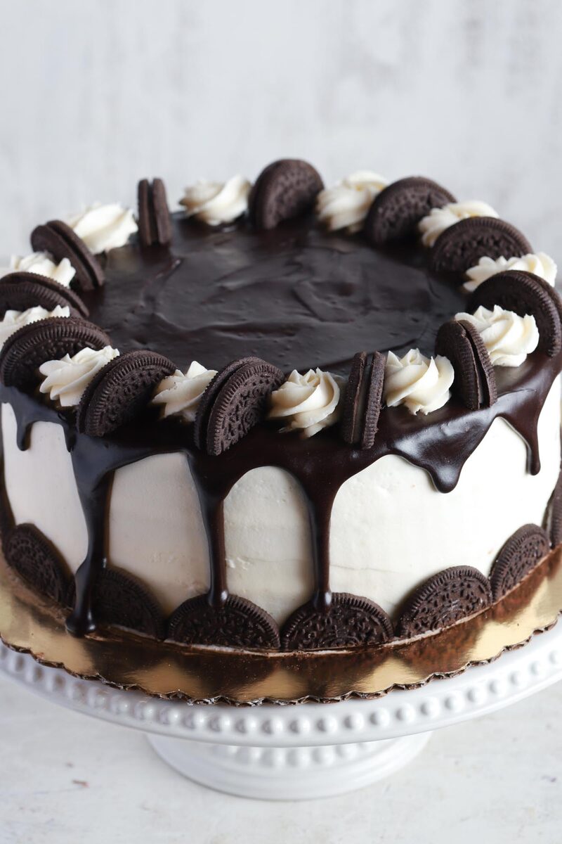 Cookies-and-cream layer cake with a chocolate ganache drip on a cake stand