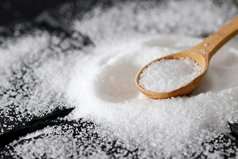 Fine white sea salt being scooped with a wooden spoon