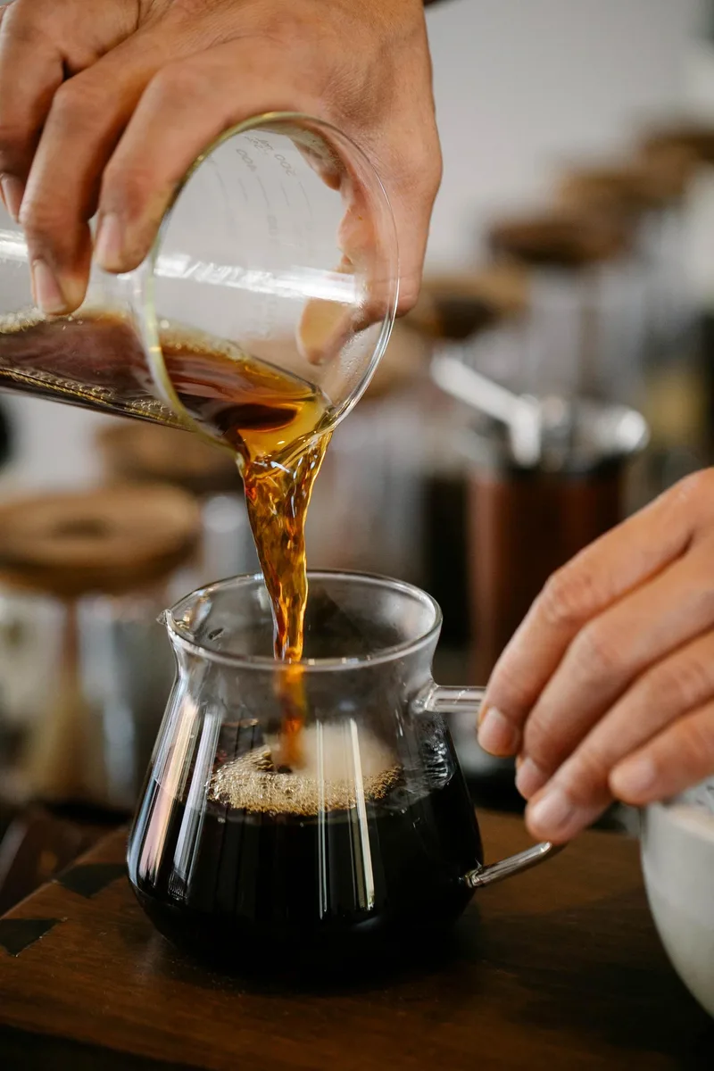 Pouring cold brew concentrate from a carafe into a glass vessel