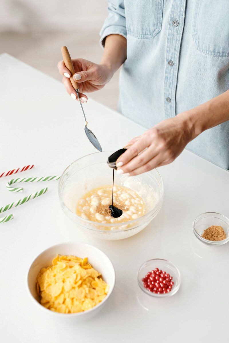 A baker pouring vanilla extract into a bowl