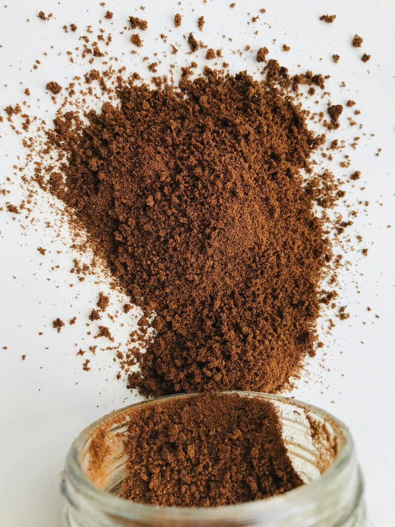 Vanilla bean powder spilling out of a jar onto a white counter